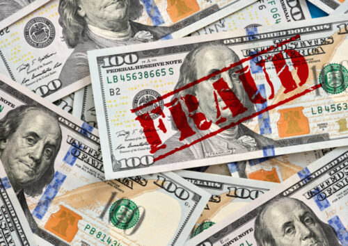Fraud concept with red stamp on one hundred dollar bills